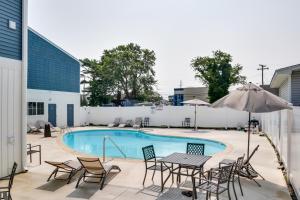 a pool with tables and chairs and an umbrella at Rehoboth Beach Vacation Rental with Community Pool! in Rehoboth Beach