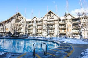 ein Gebäude mit einem Pool im Schnee in der Unterkunft The Aspens by Whiski Jack in Whistler