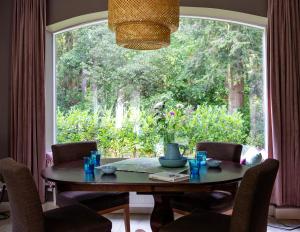 een eetkamer met een tafel en een groot raam bij Het Witte Boshuis Vierhouten in Vierhouten