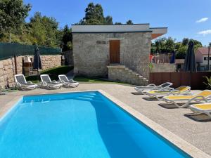a swimming pool with chairs and a house at Casa do capitão A casa ideal para férias no Gerês in Vieira do Minho