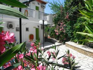 a garden with pink flowers in front of a house at Dimitris Apartments in Vasiliki