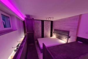 a small room with a bed with purple lighting at ParkCity Katowice in Katowice