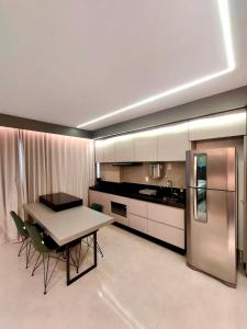 a kitchen with a table and a refrigerator at Estúdio Moderno e Elegante no Vertigo in Campo Grande