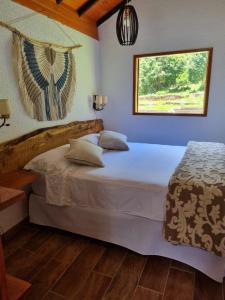 une chambre avec un grand lit blanc avec une fenêtre dans l'établissement Chalé Vale das Minas Gerais, à Camanducaia
