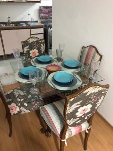 una mesa de comedor con platos y sillas azules en Apartamento encantandor-perto centro e shopping en Poços de Caldas