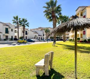 una panchina in un campo con un ombrellone in erba di Casa Domenico ad Alicante