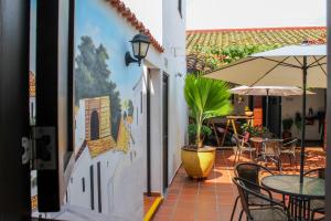 d'une terrasse avec des tables, des chaises et un parasol. dans l'établissement Hotel Colonial San Felipe, à Girón