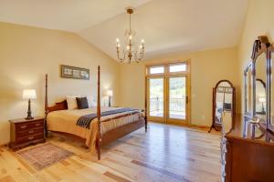 a bedroom with a bed and a chandelier at Hot Tub and Golf Course Views Luxe Sturgis Home! in Sturgis