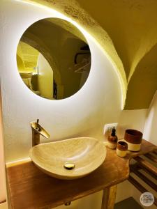 uma casa de banho com um lavatório e um espelho circular em Calamedde Guest House nel Centro Storico Pugliese em Fasano