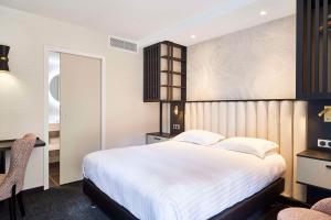 a bedroom with a large white bed and a desk at Best Western Premier Hotel des Vignes et des Anges in Pauillac