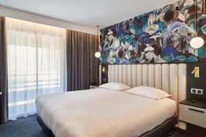 - une chambre avec un grand lit orné d'une peinture murale dans l'établissement Best Western Premier Hotel des Vignes et des Anges, à Pauillac