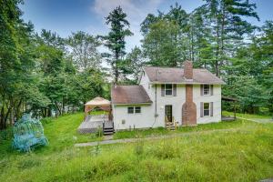 a white house on a hill in a field at Lakefront West Sand Lake Home with Beach Access! 