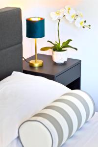 a bed with a table with a lamp and a plant at APPARTAMENTI LEONE - Vista Mare - Pet Friendly in Rimini