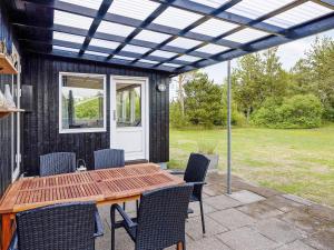 un patio con mesa de madera y sillas en 6 person holiday home in S by en Sæby