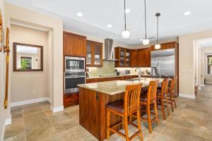 a kitchen with wooden cabinets and a island with bar stools at Big Island Holua Kai 7072 home in Kailua-Kona
