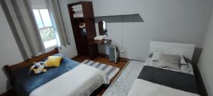 a bedroom with two beds and a window at Recanto Dorinha in Campos do Jordão