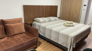 um quarto com uma cama e uma cadeira em Apartamentos Centro Poços de Caldas em Poços de Caldas