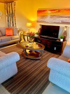 a living room with two chairs and a television at Pearls Place in Arima