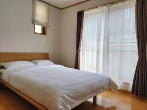 江戸川House（小岩车站400米一户建） في طوكيو: غرفة نوم بسرير مع نافذة كبيرة
