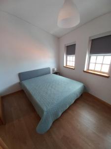 a bedroom with a bed in a room with two windows at TORREÃO HOUSE in Guarda