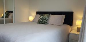 a bedroom with a white bed with two pillows at The Atrium in Mount Maunganui