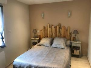 - une chambre avec un grand lit et une tête de lit en bois dans l'établissement Maison de village, à Laurens