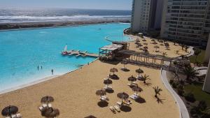 una playa con sillas y sombrillas y una piscina en Departamento resort lagunas del mar, en La Serena