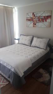 Una cama con sábanas blancas y almohadas en un dormitorio en Departamento resort lagunas del mar, en La Serena