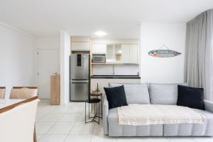 un soggiorno con divano e una cucina di Apartamento 150m da PRAIA com SACADA, WI-FI AR CONDICIONADO, PISCINA, PORTARIA 24h, PLAYGROUND e vaga de GARAGEM a Piçarras