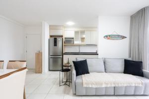 ein Wohnzimmer mit Couch und Küche in der Unterkunft Apartamento 150m da PRAIA com SACADA, WI-FI AR CONDICIONADO, PISCINA, PORTARIA 24h, PLAYGROUND e vaga de GARAGEM in Piçarras
