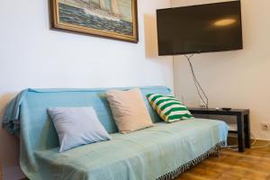 Sofá azul con almohadas y TV de pantalla plana en Apartments by the sea Stomorska, Solta - 5190 en Stomorska