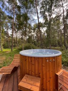 bañera de hidromasaje en una terraza de madera en el bosque en Domki Sekwoja en Dziwnów