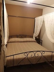 um quarto com uma cama de dossel e cortinas brancas em A cantunera o castieddu em Naro