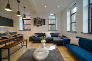 a living room with a blue couch and a table at Stylish & Elegant city centre apartment in Leeds
