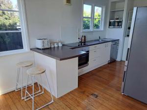 a kitchen with a counter and two stools in it at 3bdrm plus Sleepot Home, in Nelson