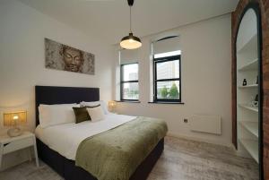 a bedroom with a large bed and two windows at Stylish & Elegant city centre apartment in Leeds