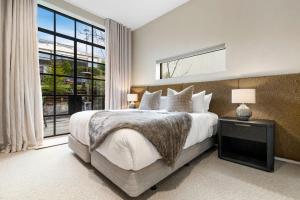 een slaapkamer met een groot bed en een groot raam bij Lakeside Terrace Luxury by Relaxaway Holiday Homes in Queenstown
