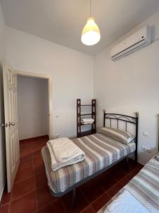 um quarto com 2 camas e uma cadeira em Apartamentos Sevilla Deluxe Rosales em Los Rosales
