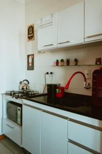 a kitchen with white cabinets and a stove top oven at Cantinho da Ernesto in Santa Maria