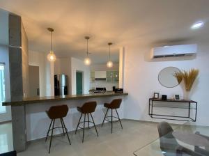 a kitchen with three bar stools and a counter at Departamento colonia Carrizal in Villahermosa