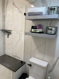 ein Badezimmer mit WC und Regalen mit Handtüchern in der Unterkunft Modern Studio Basement with Private Entrance in Centennial