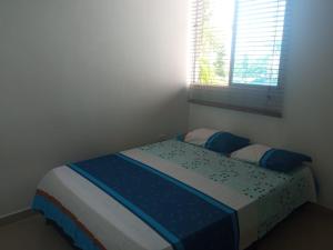 a bedroom with a bed with blue sheets and a window at Cómodo apartamento cerca al mar in Coveñas