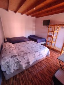 1 dormitorio con cama, TV y escalera en Hostal Perita, en San Pedro de Atacama