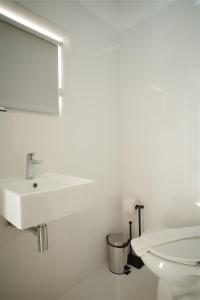 a white bathroom with a sink and a toilet at The Lizard Boutique Hotel in Kralendijk