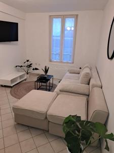 a living room with two couches and a flat screen tv at L'EDEN in Étampes