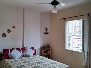 a bedroom with a bed with pillows and a window at Acolhedor com suíte e wi-fi in Praia Grande