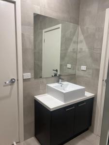 La salle de bains est pourvue d'un lavabo blanc et d'un miroir. dans l'établissement Private Rooms in Clayton South Near Monash Uni, à Clayton North
