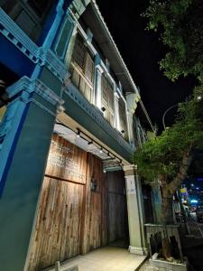 a blue building with a wooden door and a tree at 7 Wooden Lodge Ipoh City in Ipoh