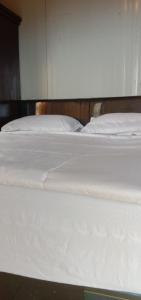 a close up of a bed with white sheets and pillows at Melbyls Hills Resort in Tomohon