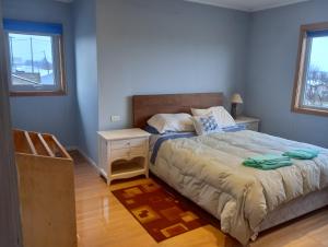 a bedroom with a bed and a nightstand and two windows at Hostal Don Luis in Purranque